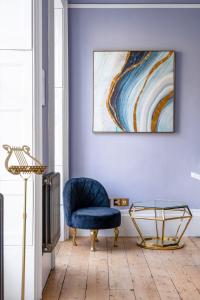 a living room with a blue chair and a painting at Darcys' View in Bath