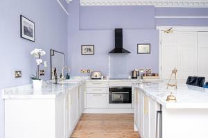 a white kitchen with white cabinets and white counter tops at Darcys' View in Bath