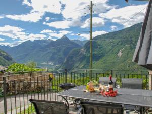 uma mesa com um copo de vinho numa varanda com montanhas em Holiday Home Rustico Ca' di Garoi by Interhome em Malvaglia