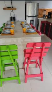 Indigo Palomino Beautiful House في بالومينو: مطبخ مع كراسي حمراء وأخضر على منضدة
