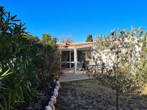 uma pequena casa branca com um pátio e árvores em Village des Sables 500 mètres de la Méditerranée. em Torreilles