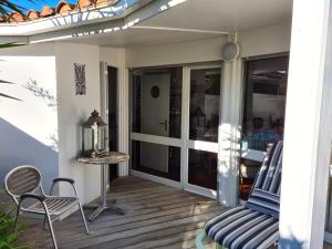 une terrasse couverte avec une chaise, une table et des portes en verre dans l'établissement Village des Sables 500 mètres de la Méditerranée., à Torreilles