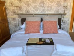 Una cama con dos almohadas y un libro. en Plumpton Court en Nawton