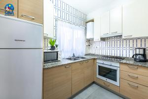 a kitchen with wooden cabinets and a white refrigerator at Apartamentos Vista Alegre Casa Azahar in Alcossebre