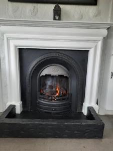 una chimenea con fuego en su interior en The Villa, en Lettermacaward