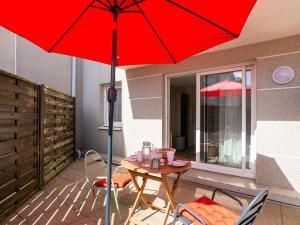 una sombrilla roja en un patio con mesa y sillas en Studio Résidence le Cotre by Interhome, en Saint-Malo