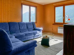 een woonkamer met een blauwe bank en ramen bij Holiday Home Casa Pina by Interhome in Malvaglia