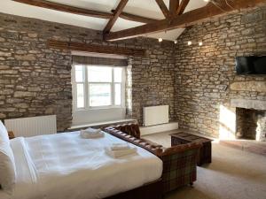 a bedroom with a large bed and a brick wall at The Greyhound Hotel in Shap