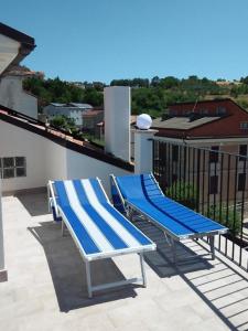 Duas cadeiras azuis e brancas sentadas numa varanda em Primae Noctis Apartments em Roccascalegna