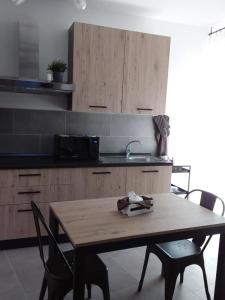 cocina con mesa de madera con sillas y fregadero en Primae Noctis Apartments, en Roccascalegna