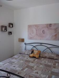 Primae Noctis Apartments في Roccascalegna: غرفة نوم بسرير مع لوحة على الحائط