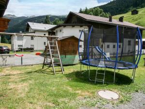 a playground with a trampoline in front of a house at Apartment Sesselebenerhof-2 by Interhome in See