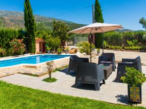 a patio with chairs and an umbrella next to a pool at Holiday Home Rincón del Sur by Interhome in Nigüelas