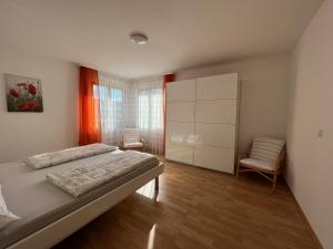 ein Schlafzimmer mit einem großen Bett und einem Stuhl in der Unterkunft Haus Lauria in Kressbronn am Bodensee