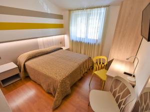 a hotel room with a bed and a desk and a chair at Apartment Stelvio by Interhome in Grosotto