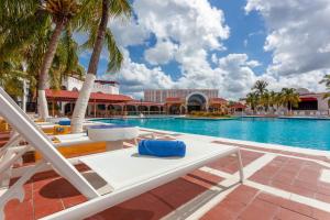 a pool at the resort with lounge chairs and palm trees at Cozumel Hotel & Resort Trademark Collection by Wyndham in Cozumel