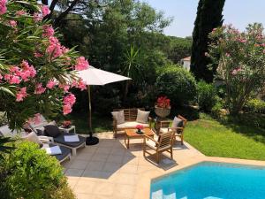 eine Terrasse mit Stühlen und einem Sonnenschirm neben einem Pool in der Unterkunft Villa Golf Azur in Saint-Raphaël