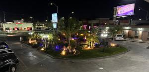 a parking lot with trees and lights at night at Garden View Inn in Fresno