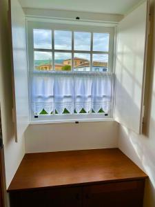 a window with a white curtain in a room at Casa do Avô José Alves in Praia da Vitória