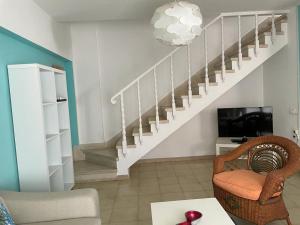 a living room with a staircase and a chair at Duplex Las Americas in Playa de las Americas