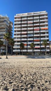 ein großes Gebäude mit Palmen vor einem Strand in der Unterkunft Apartamento Angela in Villajoyosa