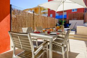 einen Tisch mit Stühlen und einem Sonnenschirm auf einer Terrasse in der Unterkunft SELECT'SO HOME - Résidence Le Poséidon - Mazet en Duplex pour 6 personnes - Piscine, Parking privé - Services hôteliers - POS-B in Bormes-les-Mimosas