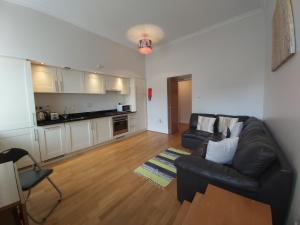 uma sala de estar com um sofá de couro preto e uma cozinha em Moat House - Highland Club em Fort Augustus