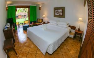 a bedroom with a large white bed and green curtains at Club Bentota in Bentota