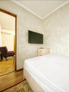 1 dormitorio con 1 cama blanca y 1 silla en Apartments Ahmetova 4 21 en Almaty