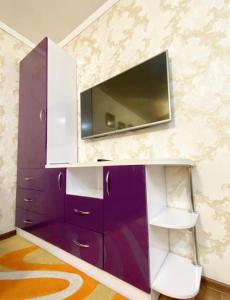 a purple cabinet with a tv on a wall at Apartments Ahmetova 4 21 in Almaty