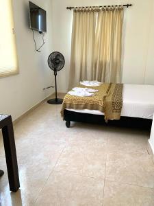 um quarto com uma cama, uma televisão e piso em azulejo em Casa Santiago Mayor em Cali