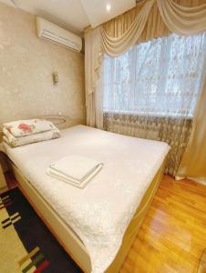 a small bedroom with a bed with a window at Apartments Ahmetova 6 32 in Almaty