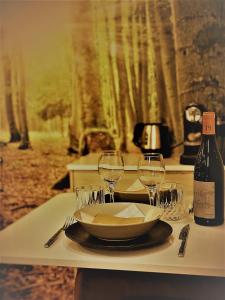 a table with a plate and wine glasses on it at Au Vingtain - Appartement & Spa atypique in Brindas