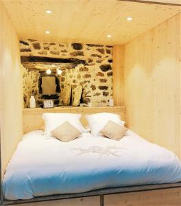 a large bed in a room with a stone wall at Au Vingtain - Appartement & Spa atypique in Brindas