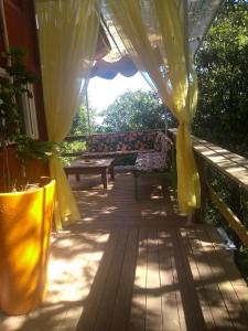 eine Veranda mit gelbem Vorhang und einer Bank in der Unterkunft Casa Container in Santo Antônio
