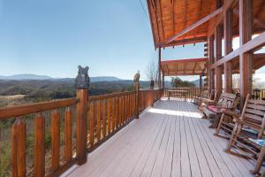 a wooden porch of a cabin with chairs on it at Heavenly Vista at Crown Point cabin in Sevierville