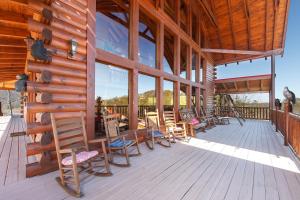 a porch of a wooden cabin with chairs and windows at Heavenly Vista at Crown Point cabin in Sevierville