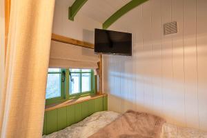 a bedroom with a bed and a tv and a window at Finest Retreats - The Shepherd's Hut at Northcombe Farm in Beaworthy