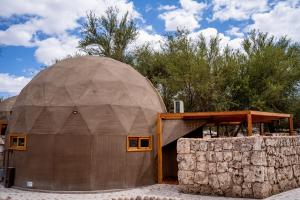 Tantakuy Eco Experience Hotel في La Huaica: منزل القبة مع جدار حجري في الأمام