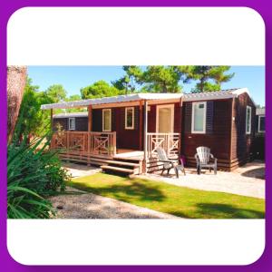 een kleine hut met een veranda en een tuin bij Mobil home Happiness33 dans camping 5 étoiles accès direct plage Vendays Montalivet in Vendays-Montalivet