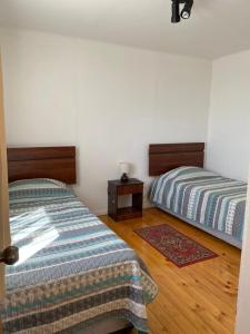 een slaapkamer met 2 bedden en een houten vloer bij Cabaña Pichilemu in Pichilemu