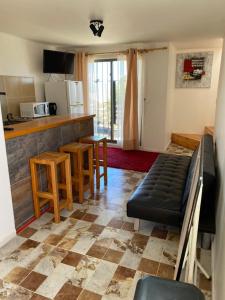 een woonkamer met een bank en een keuken bij Cabaña Pichilemu in Pichilemu
