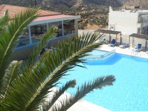 a pool with a palm tree in front of a building at Seven Stars in Karpathos