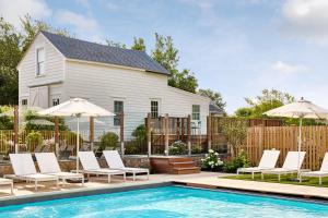 a pool with chairs and umbrellas next to a house at Block Island Beach House in New Shoreham