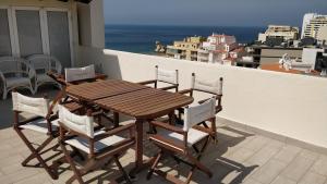 un tavolo in legno e sedie sul balcone. di Apartamento com grandes terraços em frente a Praia a Portimão