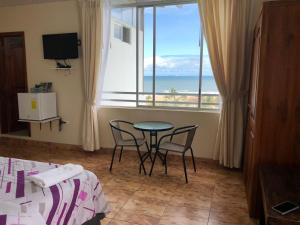 Habitación con mesa, sillas y vistas al océano. en Hotel Las Palmas en Esmeraldas