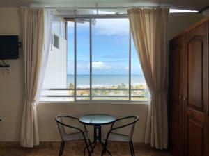 einen Tisch und zwei Stühle vor einem großen Fenster in der Unterkunft Hotel Las Palmas in Esmeraldas