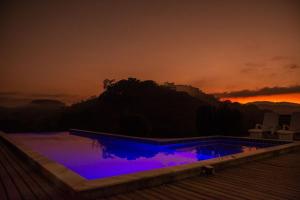 een zwembad met blauwe verlichting bij zonsondergang bij Casarão com piscina e cachoeira CUNHA SP in Cunha