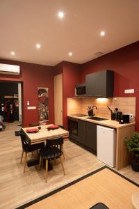 a kitchen with a table and a kitchen with red walls at Capsule Japon - Jacuzzi - Netflix & Ecran Cinéma - Xbox in Saint-Léger