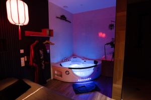 ein Schlafzimmer mit einer Badewanne in einem lila Zimmer in der Unterkunft Capsule Japon - Jacuzzi - Netflix & Ecran Cinéma - Xbox in Saint-Léger